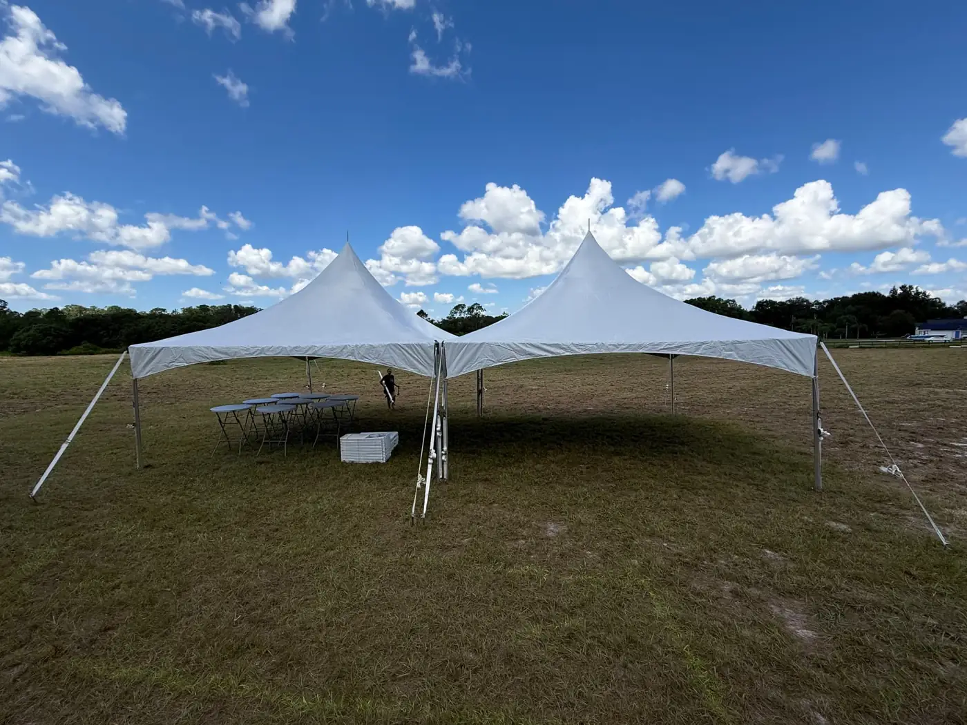 Two white peaked event tents arranged side by side on a field