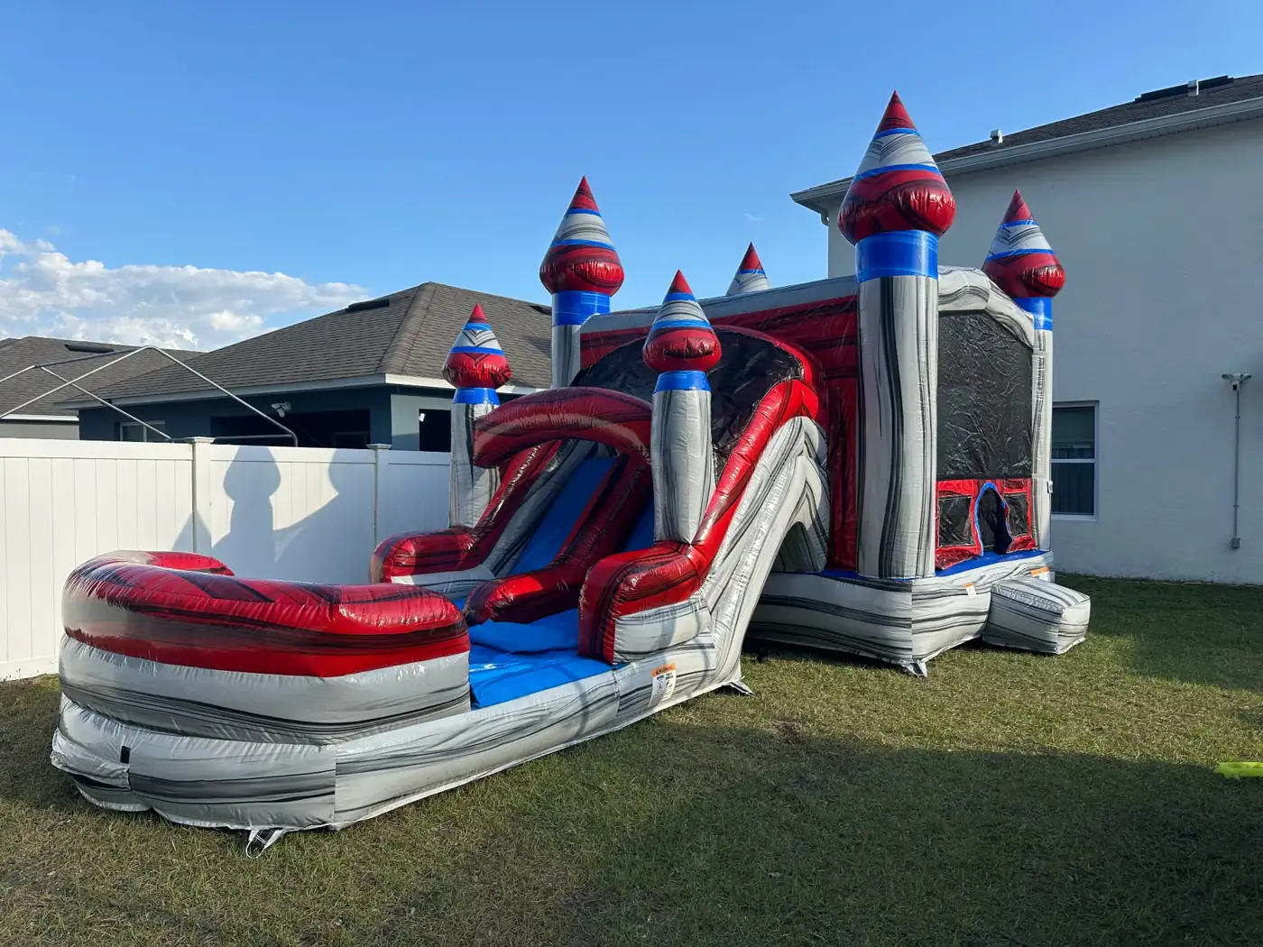Red and blue castle bounce house with slide and splash pool