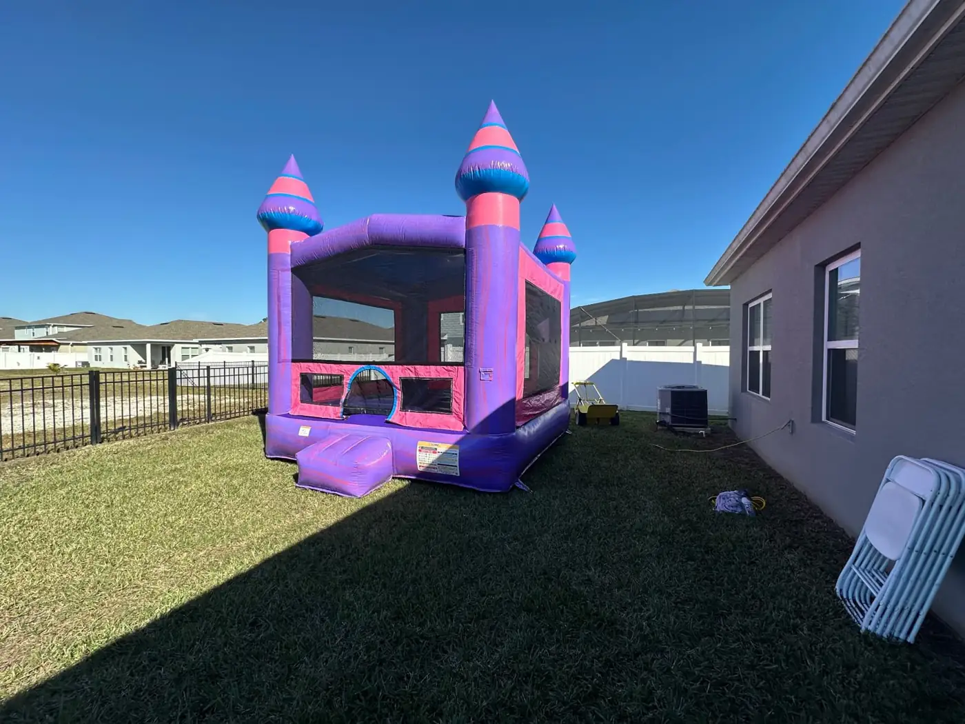 Pink and purple MJT castle bounce house beside a home