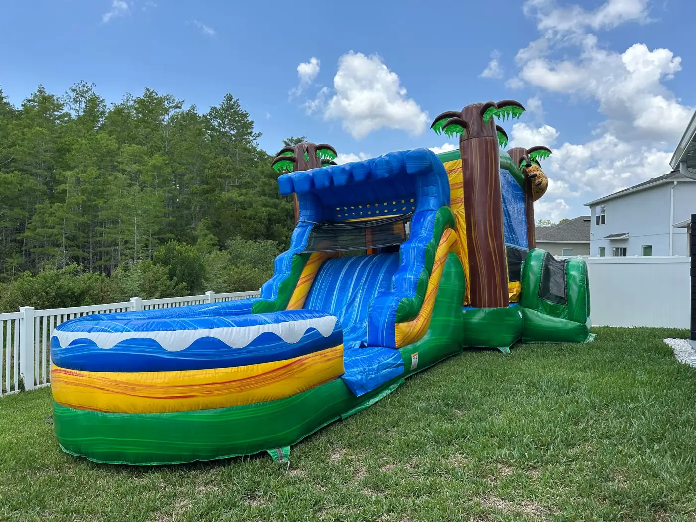 Blue and yellow tropical water slide beside a home