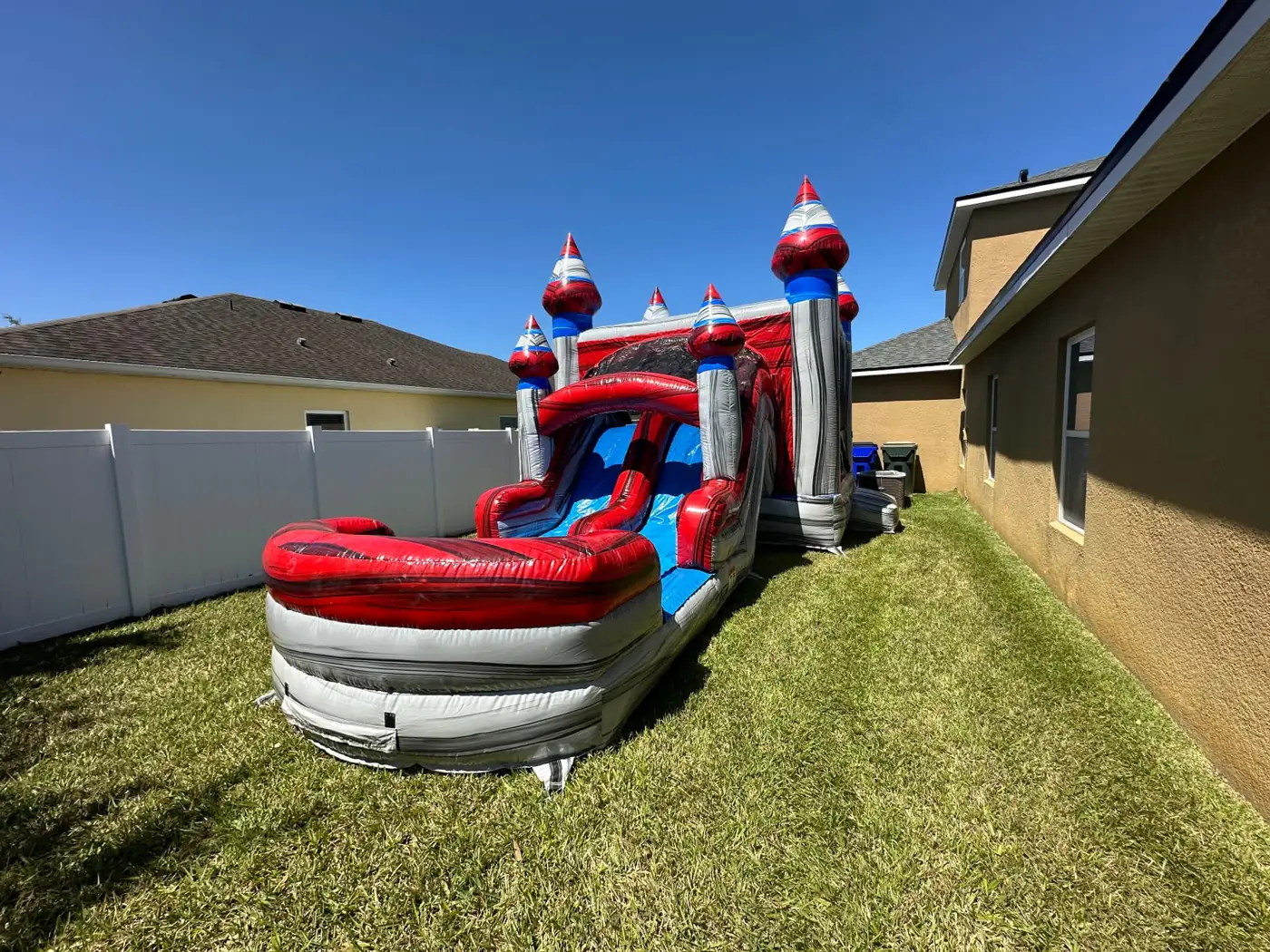 Castle bounce house and slide set up beside a home