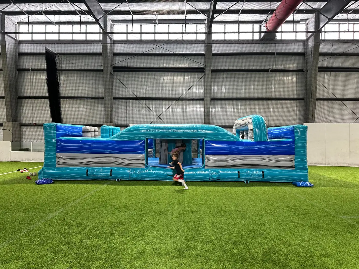 Blue inflatable obstacle course set up inside a covered venue