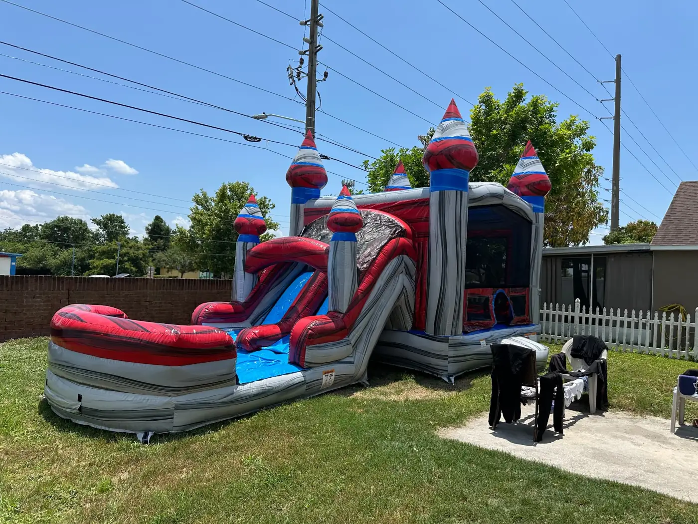 Red and blue castle bounce house with slide and splash pool on a lawn