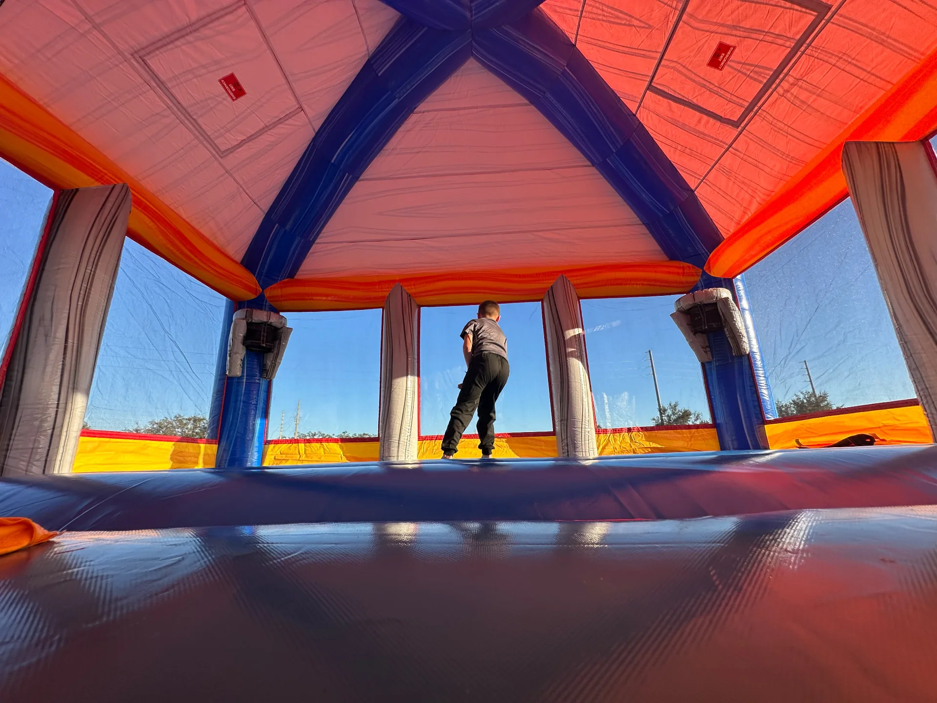 A child bouncing inside an MJT bounce house, seen from the inflatable floor