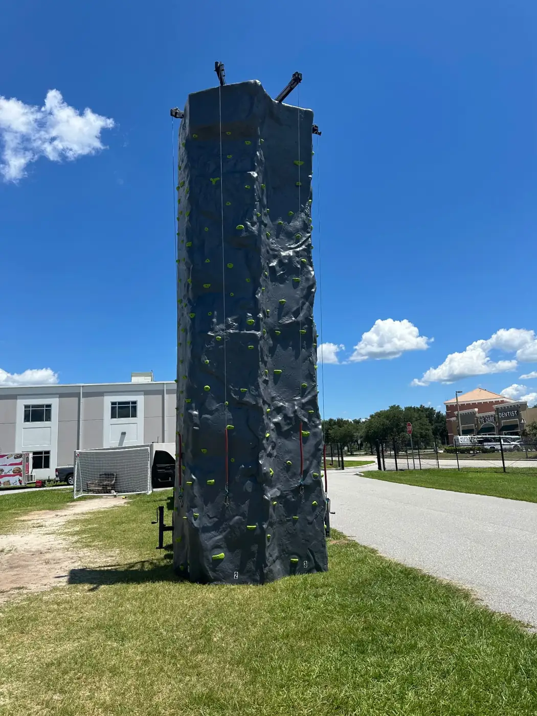 Mobile rock-climbing tower standing on a lawn beneath a blue sky