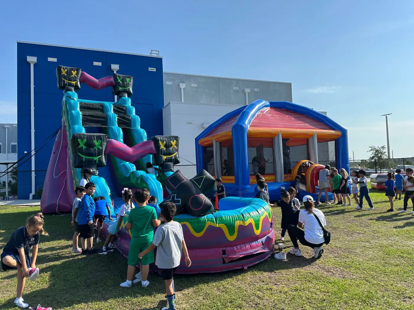 Guests beside a colorful water slide and bounce house at an outdoor event