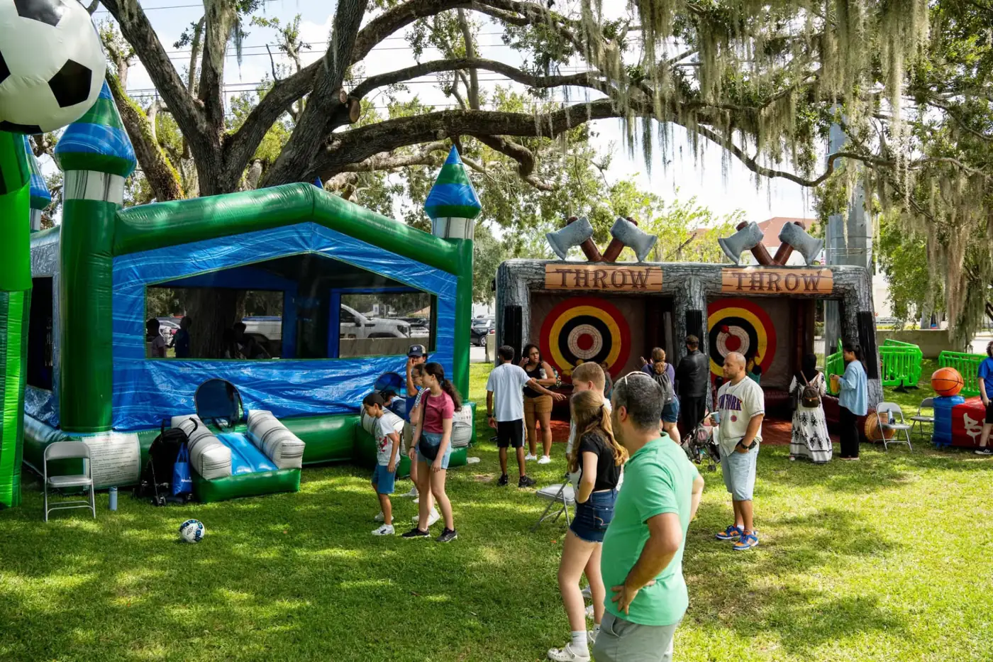 Guests beside an inflatable soccer game and axe-throwing targets