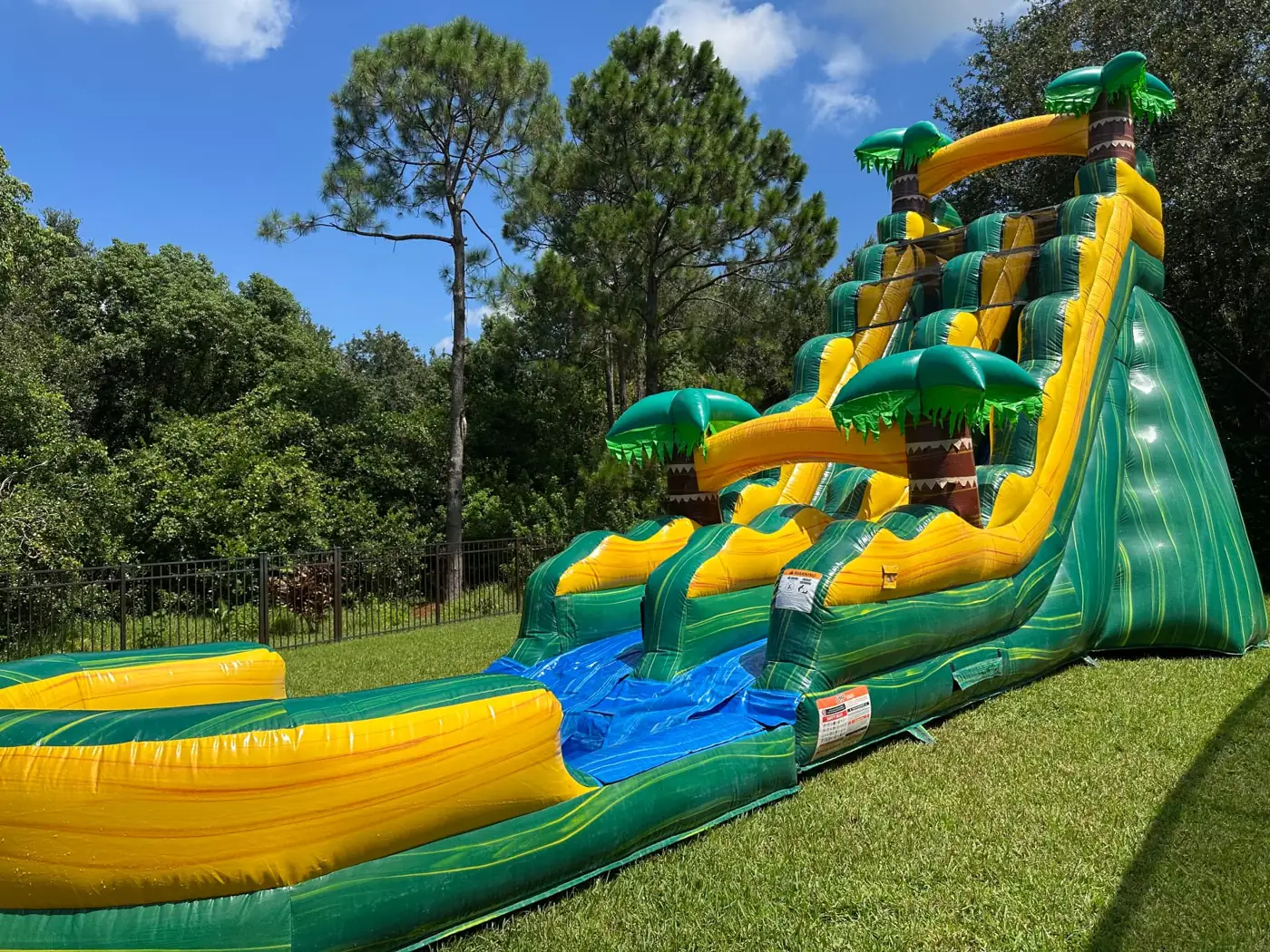 Green and yellow tropical water slide with a long splash lane and pool