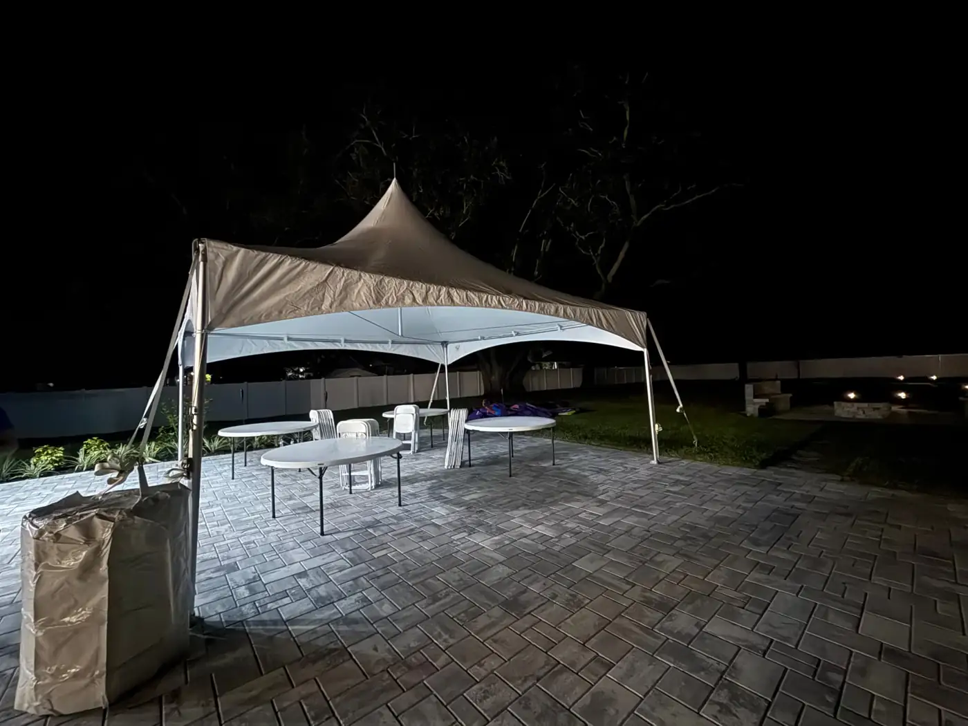 White event tent with tables and chairs on a patio at night