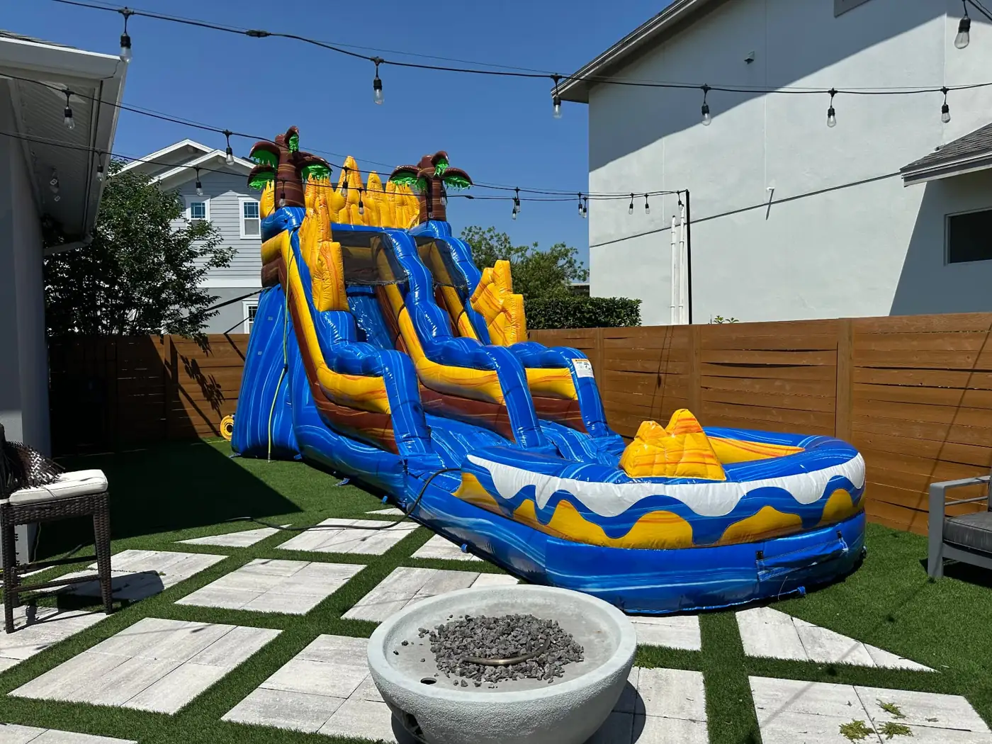 Blue and yellow water slide with a splash pool in a backyard