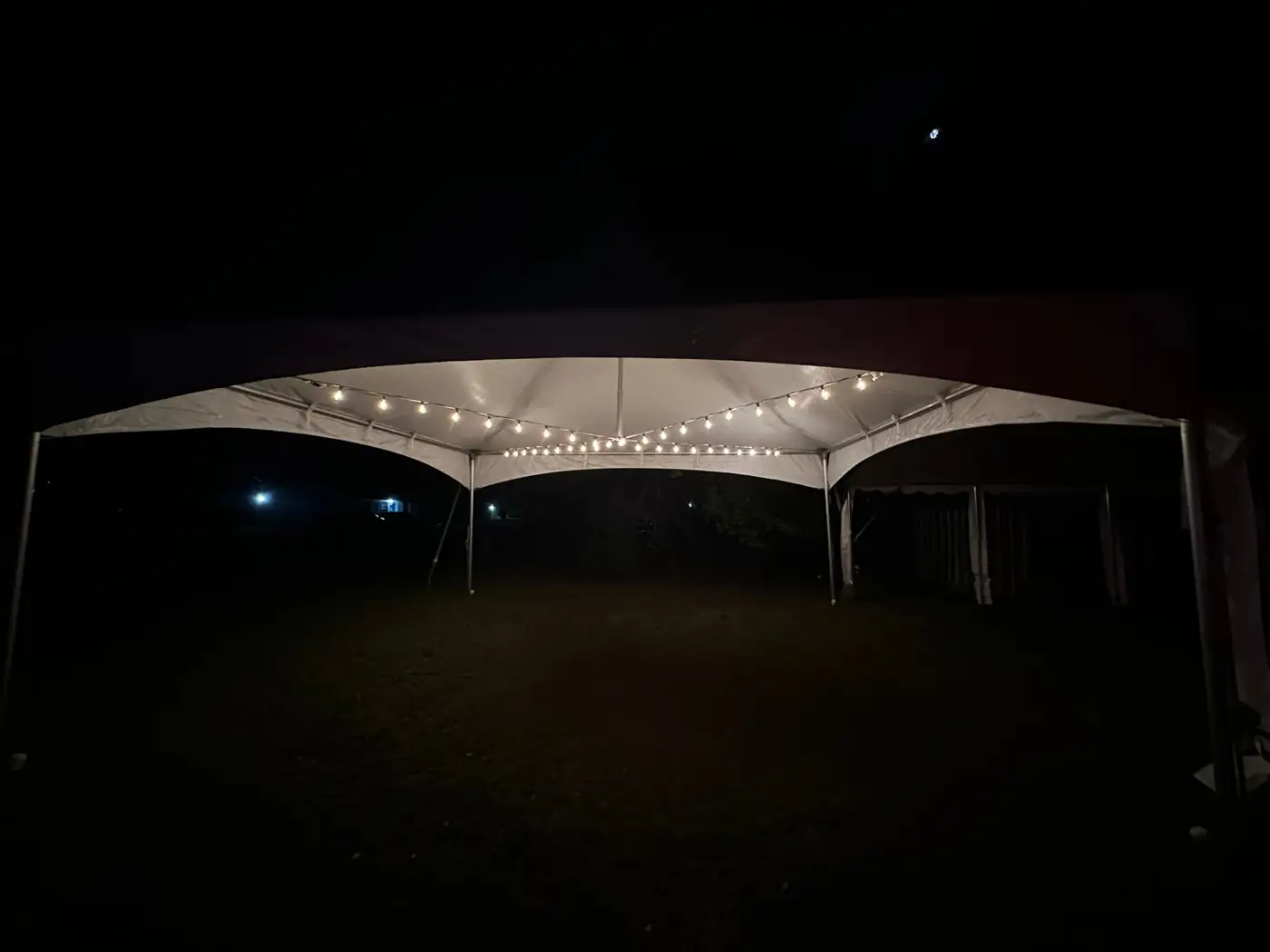 MJT event tent illuminated with string lights at night